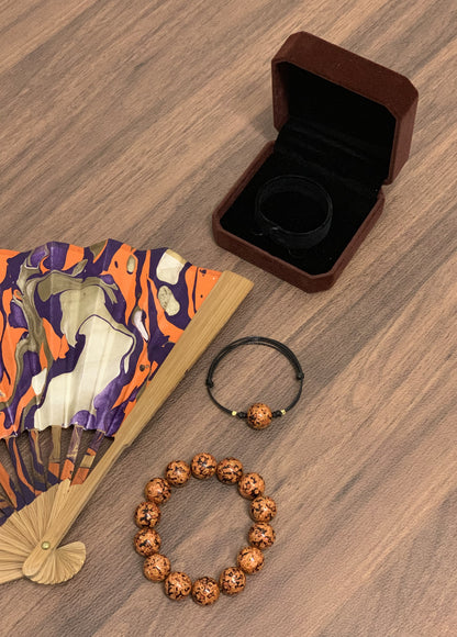 LanHeal Couple Bracelets stacked with an opening folding fan displayed on a wooden table, highlighting the intricate craftsmanship and design.