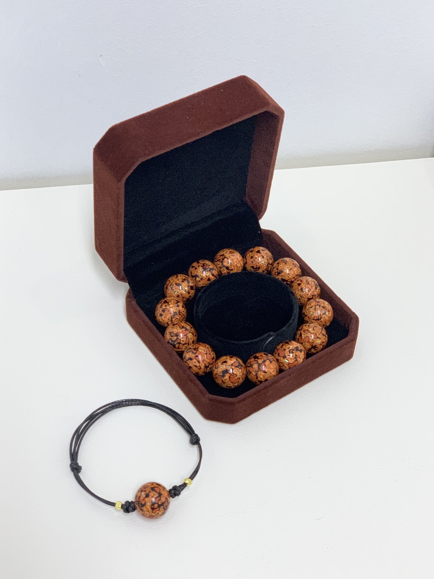 LanHeal Couple Bracelets made of sandalwood covered with Chinese lacquer in orange and black, featuring mother-of-pearl crafts, one in a storage box and the other beside it on a white background.