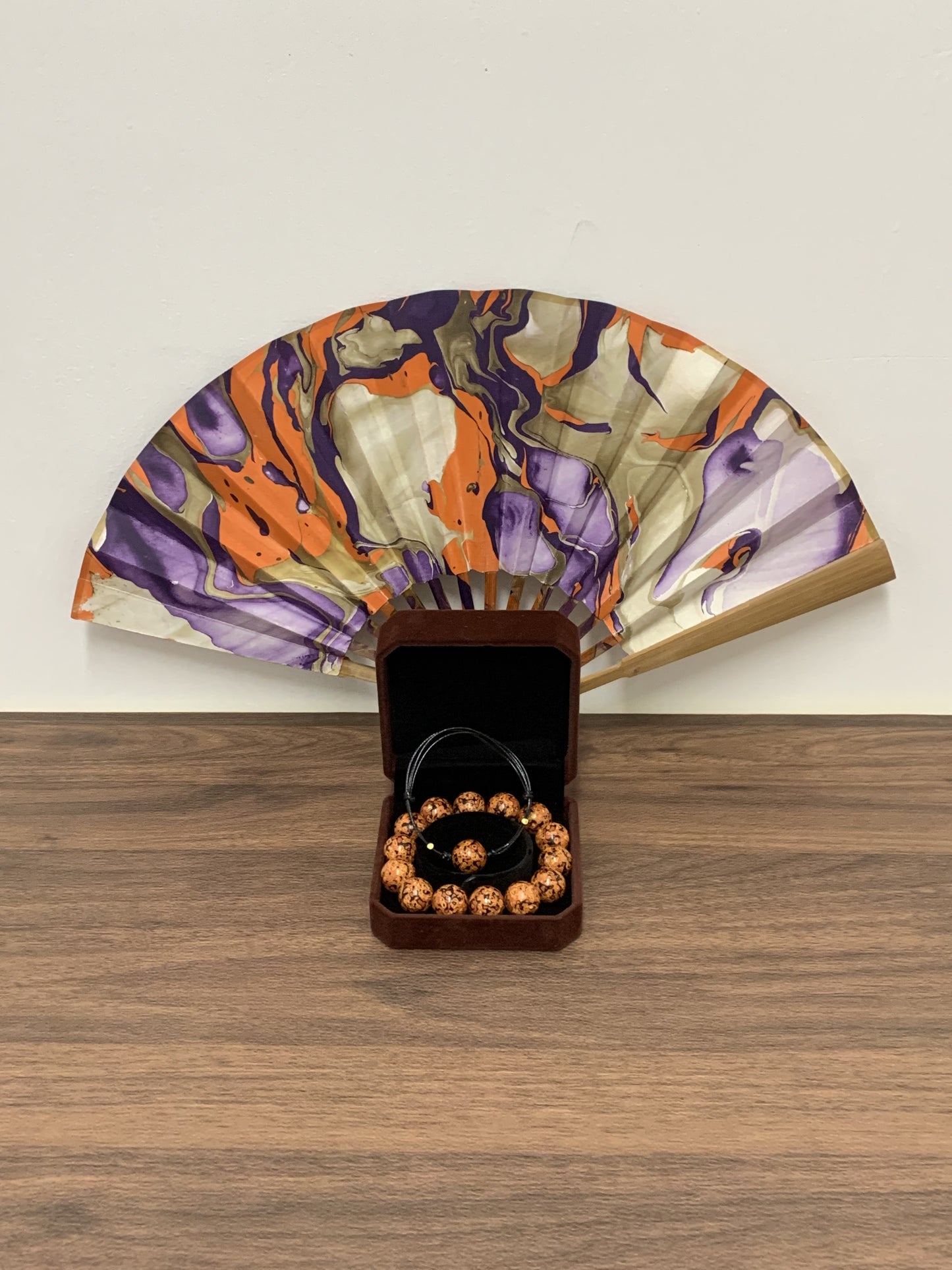 LanHeal Chinese lacquer bead bracelets and folding fan displayed on a wooden table.
